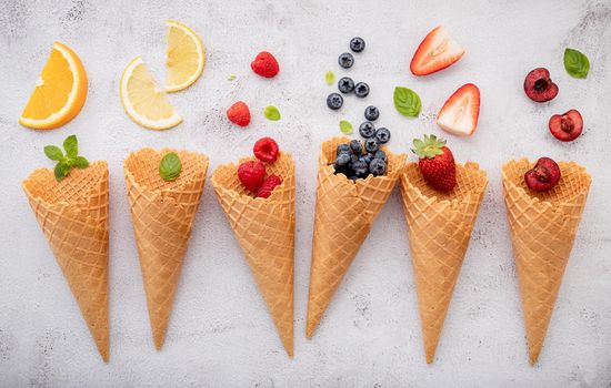 Various of fruits  in cones blueberry ,strawberry ,raspberries and strawberry setup on white stone background . Summer and Sweet menu concept.