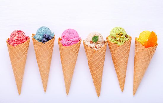 Various of ice cream flavor in cones blueberry ,strawberry ,pistachio ,almond ,orange and cherry setup on white wooden background . Summer and Sweet menu concept.