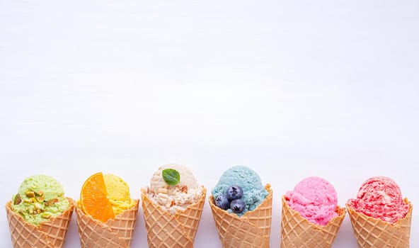 Various of ice cream flavor in cones blueberry ,strawberry ,pistachio ,almond ,orange and cherry setup on white wooden background . Summer and Sweet menu concept.