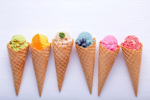 Various of ice cream flavor in cones blueberry ,strawberry ,pistachio ,almond ,orange and cherry setup on white wooden background . Summer and Sweet menu concept.