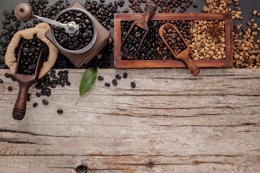 Various of roasted coffee beans in wooden box with manual coffee grinder setup on shabby wooden background.