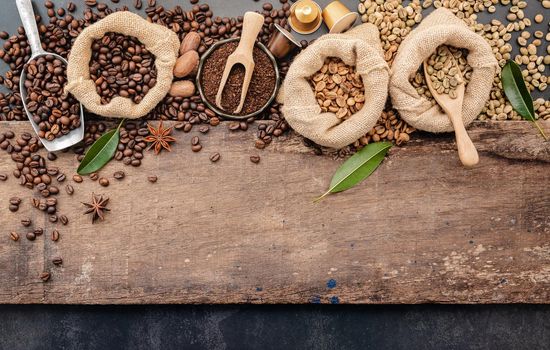 Background of various coffee , dark roasted coffee beans , ground and capsules with scoops setup on wooden background with copy space.