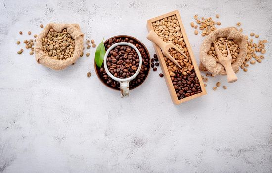 Roasted coffee beans with scoops setup on white concrete background.