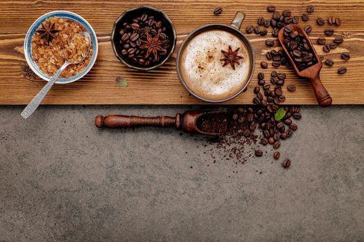 Roasted coffee beans with coffee cup setup on dark stone background.