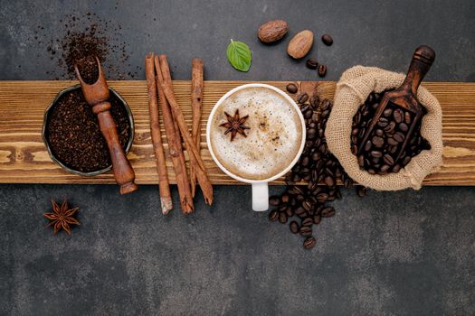 Roasted coffee beans with coffee powder and flavourful ingredients for make tasty coffee setup on dark stone background.