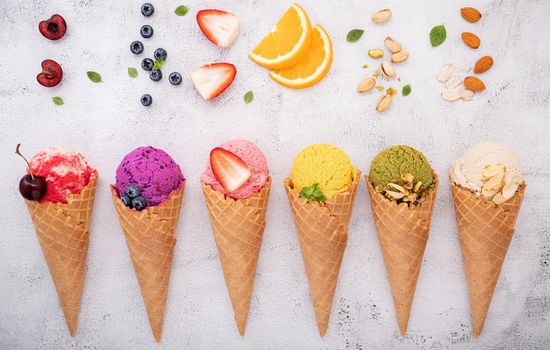 Various of ice cream flavor in cones blueberry ,pistachio ,almond ,orange and cherry setup on white stone background . Summer and Sweet menu concept.