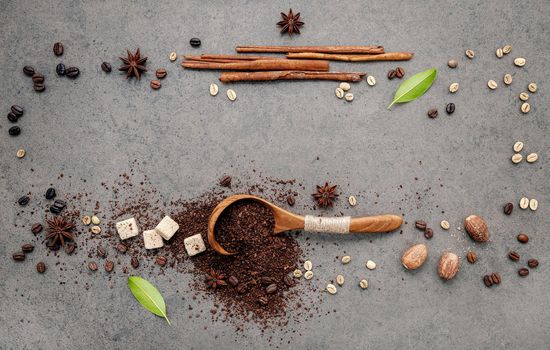 Background of dark roasted coffee beans and coffee powder with scoops setup on dark concrete background with copy space.