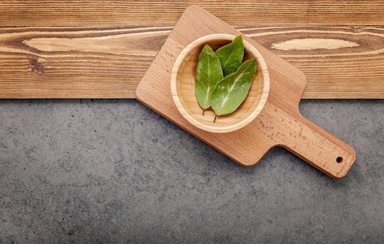 The bay leaves on cutting board set up on shabby wooden background with copy space .