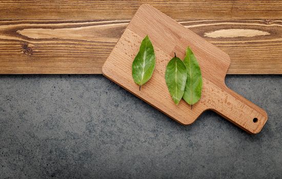 The bay leaves on cutting board set up on shabby wooden background with copy space .