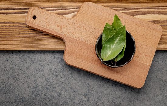 The bay leaves in ceramic bowl on shabby wooden background with copy space .