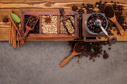 Various of roasted coffee beans in wooden box with manual coffee grinder setup on shabby wooden background.