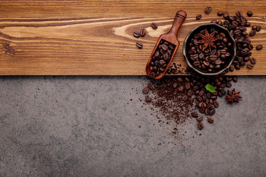 Roasted coffee beans with coffee powder setup on dark stone background.