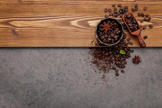 Roasted coffee beans with coffee powder setup on dark stone background.