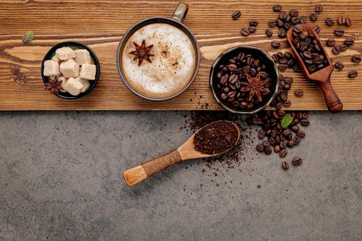 Roasted coffee beans with coffee cup setup on dark stone background.