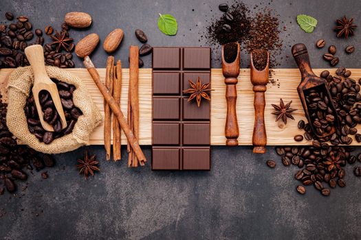 Roasted coffee beans with coffee powder and flavourful ingredients for make tasty coffee setup on dark stone background.