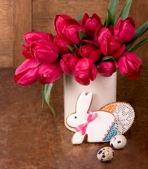 Pink tulips and easter bunny cookie on wooden background. Spring or easter concept