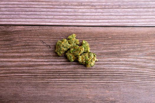 A Small Pile of Bright Green and Orange Medicinal Cannabis on a Brown Wooden Background