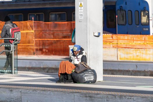 terni,italy february 24 2021:clochard black woman with black bags sitting at the station