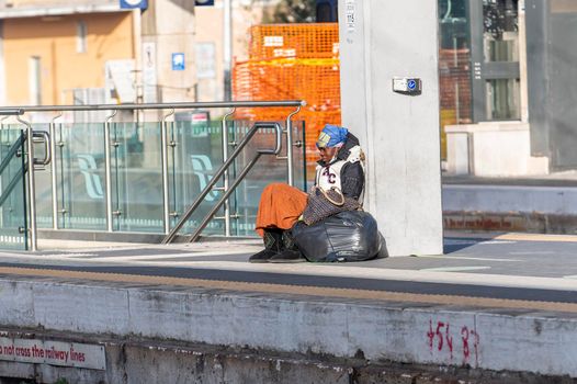 terni,italy february 24 2021:clochard black woman with black bags sitting at the station