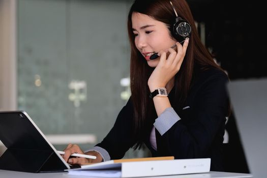 Asian businesswoman in headphones looking at laptop, watching good webinar, consulting client, distance learning languages, making notes, happy man participating online conference