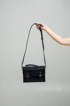 Small black leather bag in a woman's hand on a white background. Shoulder handbag. Style, retro, fashion, vintage and elegance