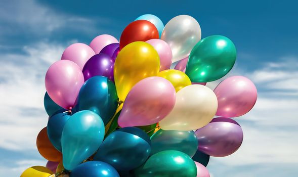 Lots of colorful balloons on the blue sky background with clouds