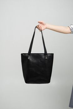 Small black leather bag in a woman's hand on a white background. Shoulder handbag. Style, retro, fashion, vintage and elegance