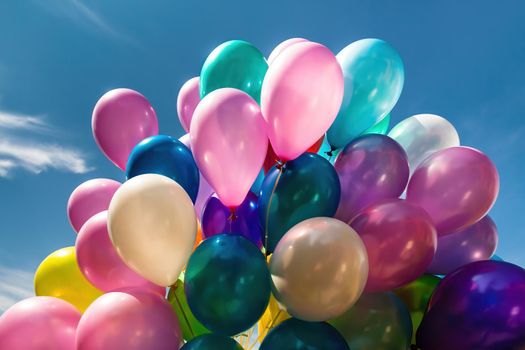 Lots of colorful balloons on the blue sky background with clouds