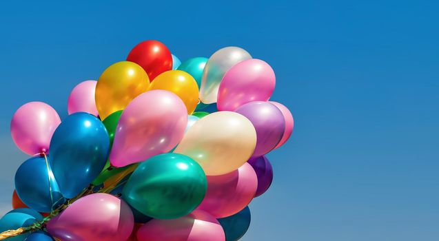 Lots of colorful balloons on the blue sky background with clouds