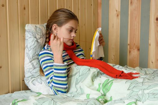 Sick girl lying in bed is embroidering on the hoop