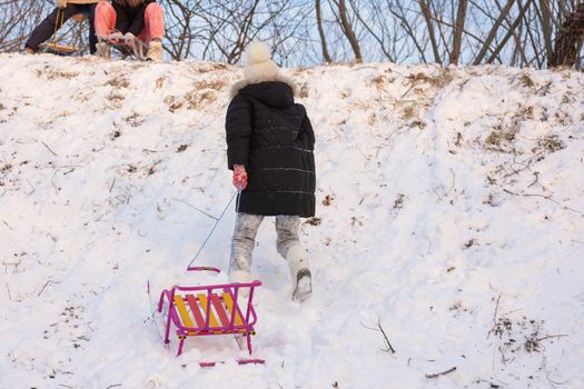 A girl runs with a sled up the hill
