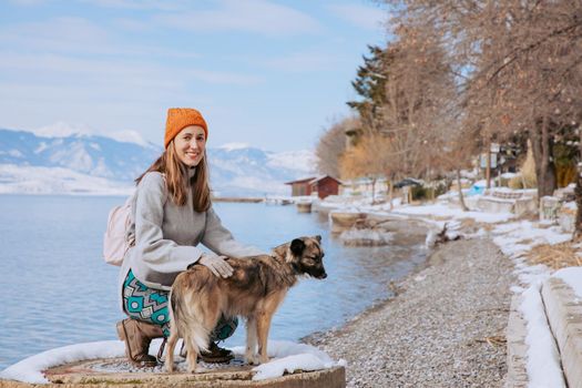 Photo of a woman walking her dog on a lake shore in winter