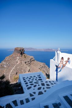 Santorini Greece, young couple mid age European and Asian on vacation at the Greek village of Oia Santorini Greece, luxury vacation Santorini. mid age man and woman watching sunset Santorini