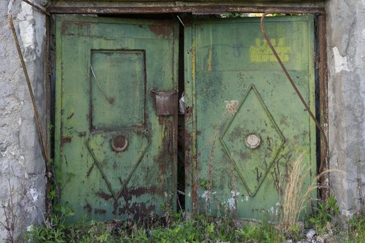 Old rusty metal gate on the background of a gray brick wall.
