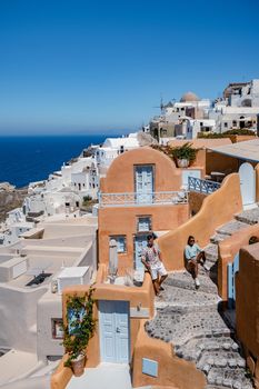 Santorini Greece, young couple mid age European and Asian on vacation at the Greek village of Oia Santorini Greece, luxury vacation Santorini. mid age man and woman watching sunset Santorini