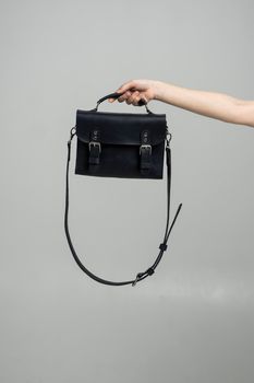 Small black leather bag in a woman's hand on a white background. Shoulder handbag. Style, retro, fashion, vintage and elegance