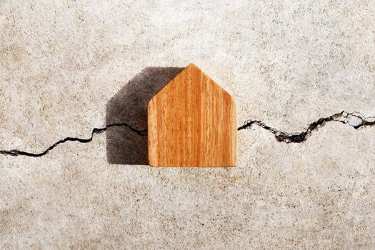 Miniature house on cracked cement wall texture background. Top view