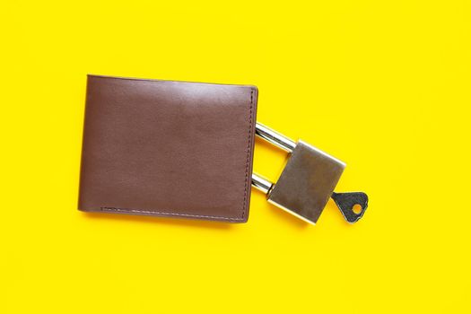 Wallet with padlock and key on yellow background. Copy space