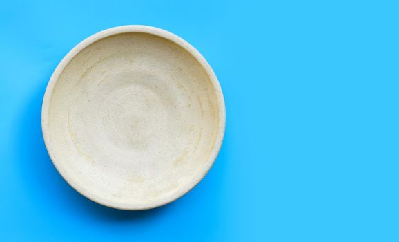 Empty pottery plate on blue background. Copy space