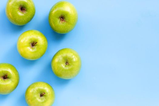 Green apples on blue background. Copy space