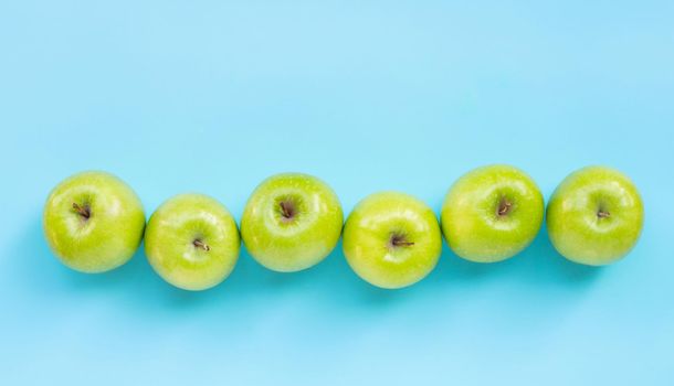 Green apples on blue background. Copy space