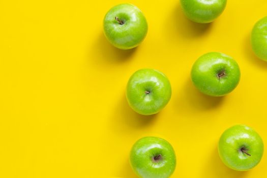 Green apples on yellow background. Copy space