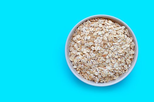 Oat flakes in bowl on blue background. Healthy food concept