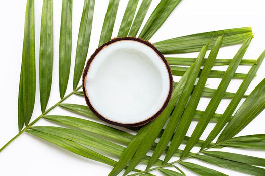 Half coconut on tropical palm leaves on white background. Top view