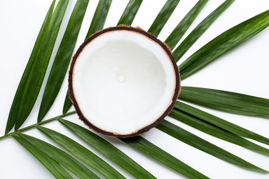 Half coconut on tropical palm leaves on white background. Top view