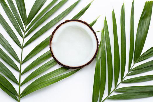 Half coconut on tropical palm leaves on white background. Top view