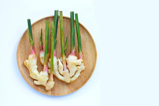 Fresh young ginger on wooden plate on white background. Copy space