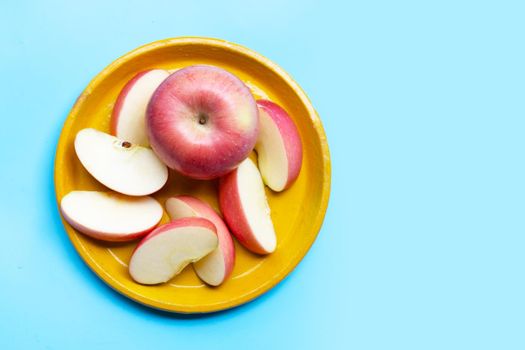 Fresh and juicy apples on yellow plat on blue background. Copy space