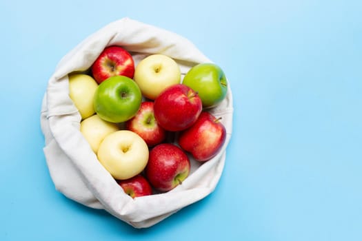 Fresh and juicy apples in cloth bag on blue background. Copy space