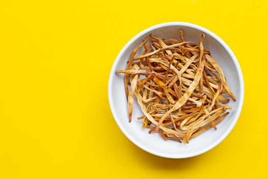 Dried Lily Buds on white bowl on yellow background. Copy space